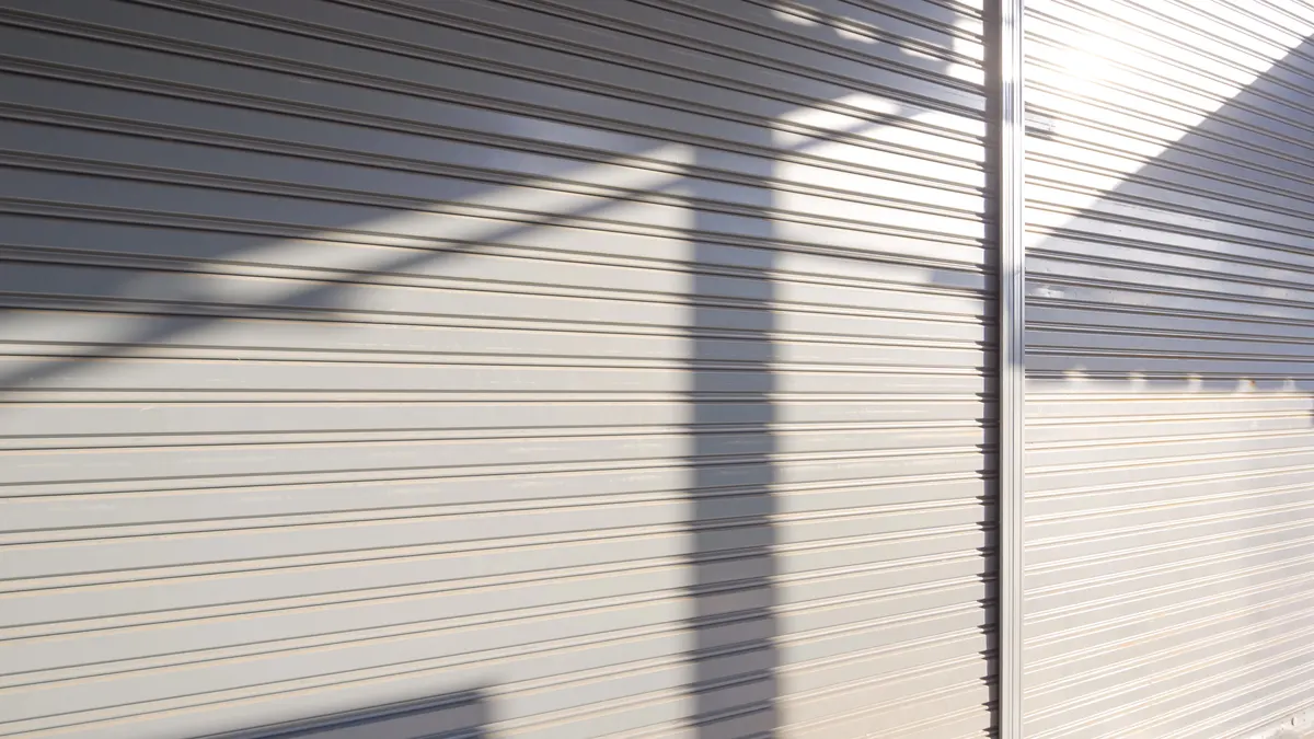 Lames de volet roulant éclairées en lumière rasante, ombres portées sur le tablier